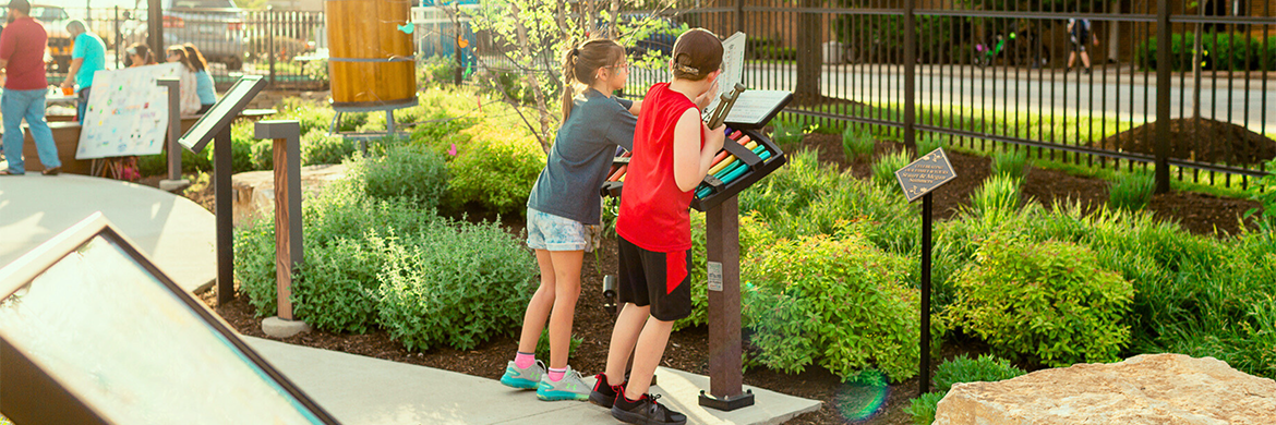 A girl and a boy playing with the instruments provided within the library gardens